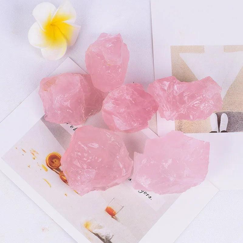 MLD Wholesale Crystals rough pink rose quartz chunks on white paper with plumeria flower wholesale rose quartz raw stones