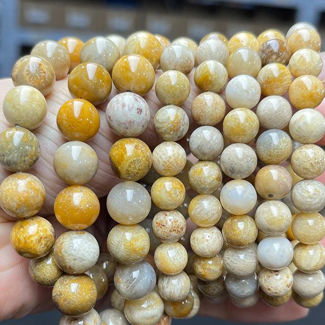 coral jade bracelet wholesale polished round yellow and cream bead strands held in hand for jewelry making